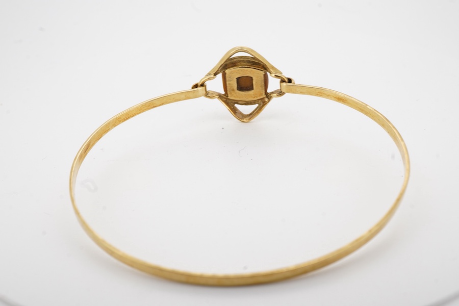 A modern continental 18k and single stone tiger's eye quartz set bangle, gross weight 7 grams.